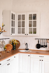 Wooden counter with white sink and utensils near light wall in kitchen