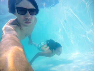pai e filha fazendo mergulho em piscina 