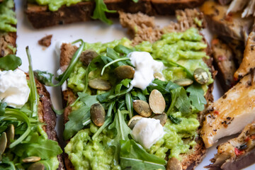 Smashed avocado on Toast with Labneh, Lemon, Parsley, Cheese, Edamame and different dried seeds, sunflower and pumpkin, very healthy and vegan green breakfast made by organic ingredients, healthy food