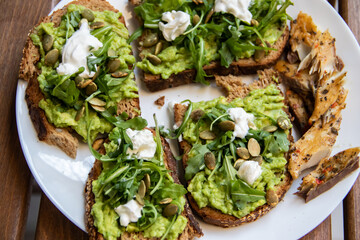 Smashed avocado on Toast with Labneh, Lemon, Parsley, Cheese, Edamame and different dried seeds, sunflower and pumpkin, very healthy and vegan green breakfast made by organic ingredients, healthy food