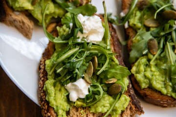Smashed avocado on Toast with Labneh, Lemon, Parsley, Cheese, Edamame and different dried seeds, sunflower and pumpkin, very healthy and vegan green breakfast made by organic ingredients, healthy food