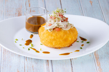 Papa rellena de carne con salsa de carne adornada con tomate, cebolla, aperitivo ecuatoriano