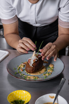 Chef Mujer adulta estilizando un corviche de cangrejo para servir al comensal