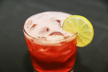 Vibrant Red Beverage with Lemon Garnish in Glass - Close-Up Perspective