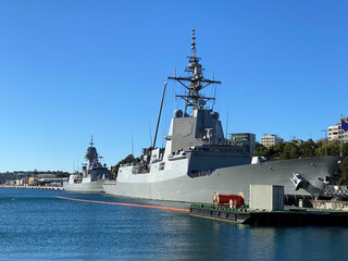 Military ships in the port of coastal city. Navy boats moored to a quay. Battleship in port. A country's fleet and marine defenses in a harbor.