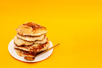homemade pancakes on a white plate with a golden spoon, copy space