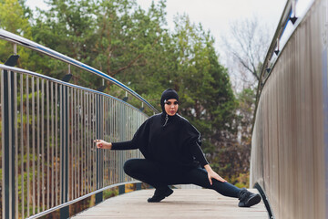 Hijab girl exercising on walkway bridge in early morning. Muslim woman wearing sports clothes doing stretching workout outdoors.