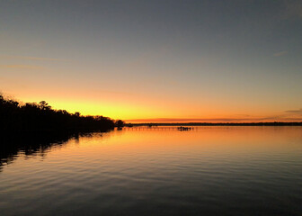 Sun setting behind trees along the shoreline of the St. Johns River in Florida