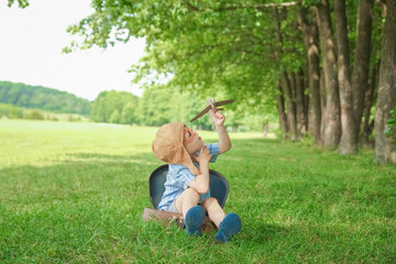 Obraz premium A Baby boy by the plane plays on nature in the park. Boy on vacation pilot.