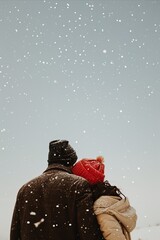 Winter love story. Back view of loving couple hugging and looking at each other while standing in snowy field