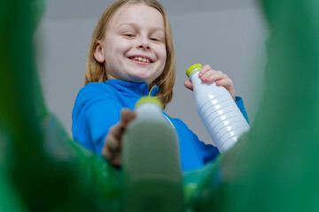 Low angle view a child sorting plastic bottles recycle bin in home. Disposal of milk bottles...