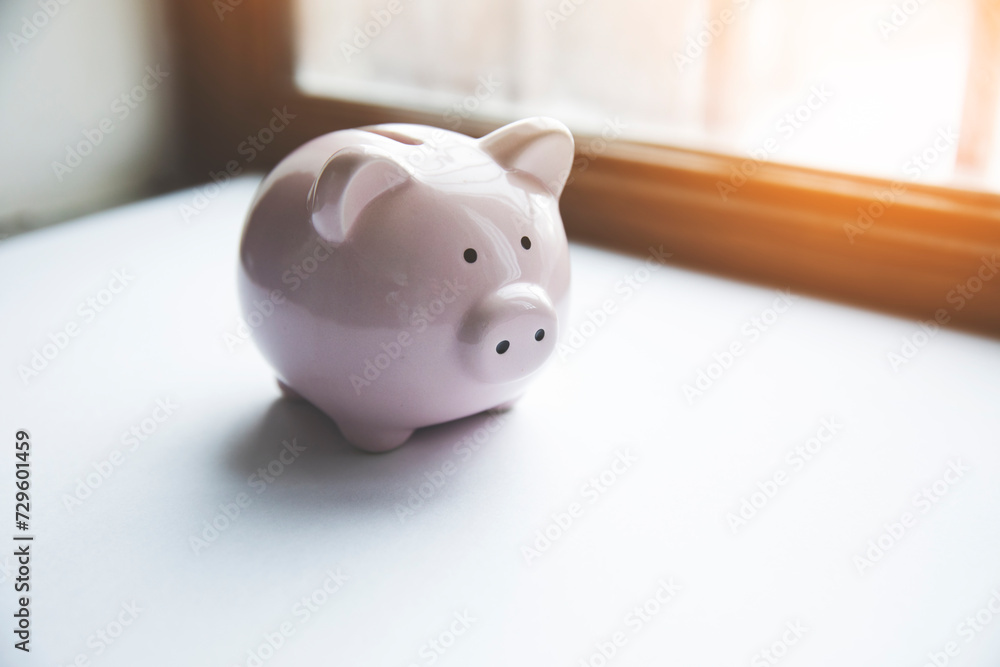 Poster a piggy bank sitting on a table in front of a window