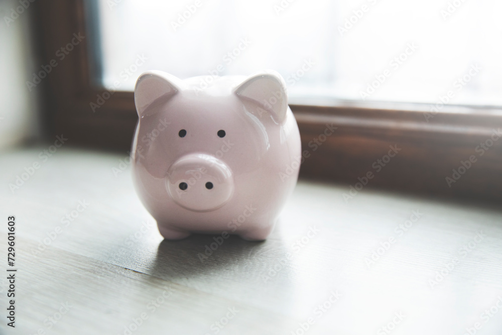 Poster a piggy bank sitting on a table in front of a window