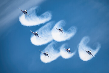 Formation of six aircraft against blue sky with braids of smoke