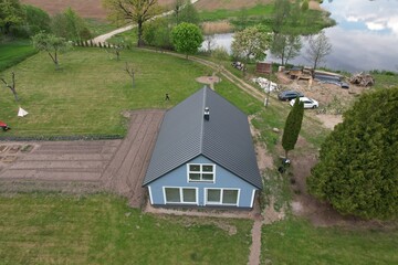 Photo of a farmhouse by the river from the sky, a Scandinavian-style house is being built by the river in Lithuania