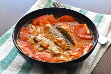 Instant noodles soup with canned sardines and tomato in a bowl. 