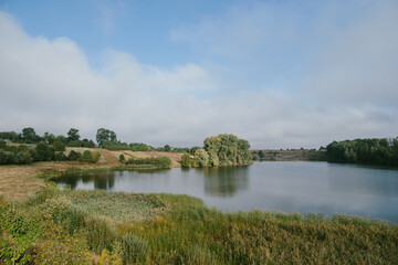 Fototapeta premium A picturesque landscape with a pond near the village.