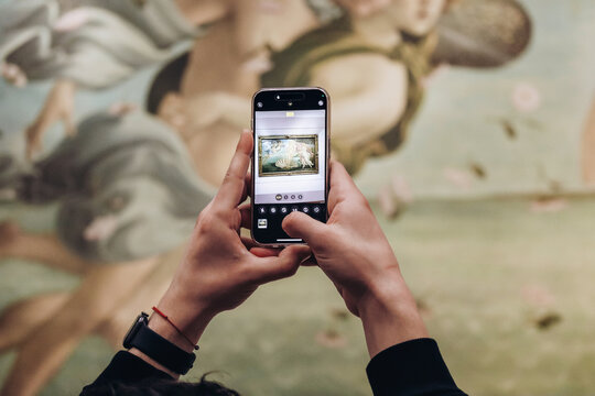 Florence, Italy - 29 December, 2023: Close-up of hands taking a phone picture of Botticelli's "Venus" at the Uffizi Gallery in Florence