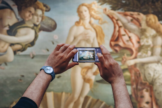 Florence, Italy - 29 December, 2023: Close-up of hands taking a phone picture of Botticelli's "Venus" at the Uffizi Gallery in Florence