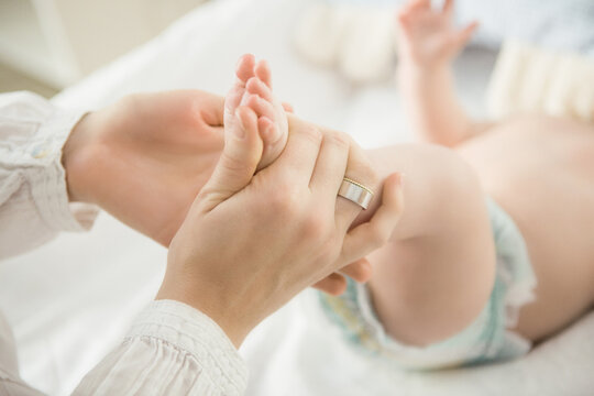 Young mother massaging the feet of her baby boy. Munich, Germany