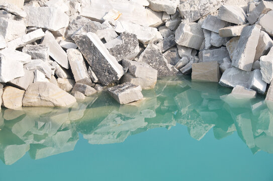 large limestone blocks falling into a brilliant green blue pool of water at a limestone quarry in Indiana. Good background image.