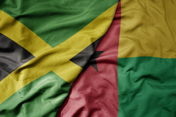 big waving national colorful flag of guinea bissau and national flag of jamaica .