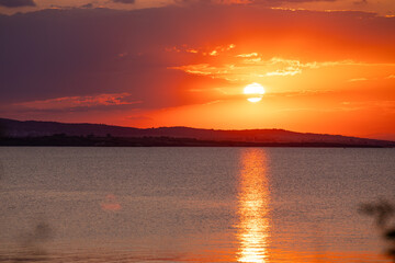 Incredible amazing, colorful summer sunsrise in Bulgaria Black coast. Orange sunset sky and reflection in the blue water.