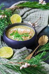 Bol japonais avec de la soupe,  feuilles de roquette, demi-citron vert et cuiilère en forme de coquillage