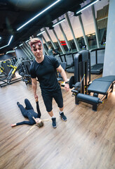 Muscular man and woman are engaged in gym workout. They are doing exercises with rope.