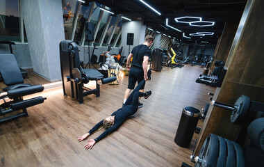 Fototapeta na wymiar Young man doing push ups with his personal trainer at the gym