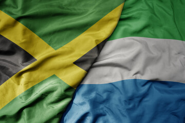 big waving national colorful flag of sierra leone and national flag of jamaica .