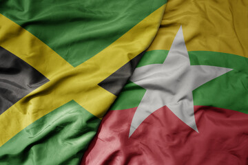 big waving national colorful flag of myanmar and national flag of jamaica .