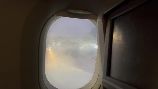 4K steady footage showing aircraft's illuminator with horrible wintery weather outside being shut in preparation for a long-haul long flight. Aviation, aviation transport, traveling, hardships when tr