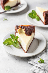Piece of homemade chocolate cheesecake with mint leave on a plate on white textured background