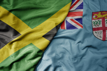 big waving national colorful flag of Fiji and national flag of jamaica .