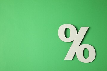 Wooden percent sign on green background, top view