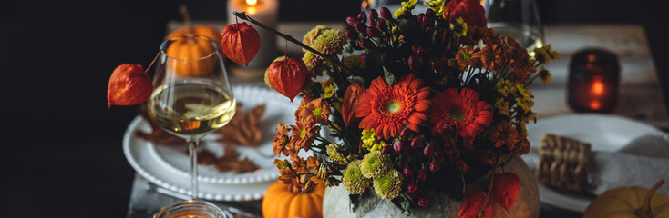 Atmospheric autumn elegant beautiful table setting with pumpkins for a wedding or thanksgiving family celebration. Fall decoration countryside rustic style, cozy home atmosphere , candles, wine banner
