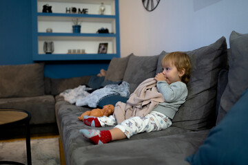 Little baby girl laying on a couch with her blanket, ready to sleep