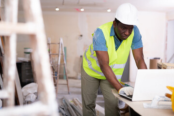 Focused african american engineer working on an construction site indoors checks a home renovation...