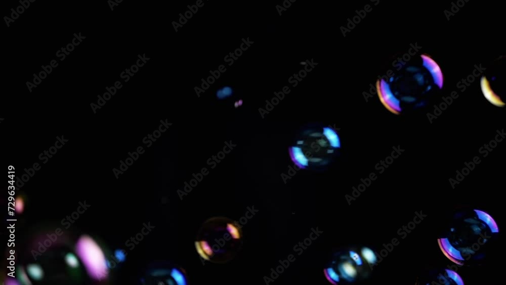 Poster colorful soap bubbles fly in empty space on isolated black background. colorful lights. many rainbow