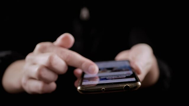 Female Fingers Scroll News Feed in Social Networks on a Mobile Phone. Close-up. A smoking girl browsing mobile applications on a smartphone at night in a smoky dark room. Smoke screen. Lifestyle.