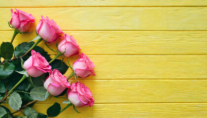 Top view image of pink rose flowers composition over wooden yellow background .Flat lay