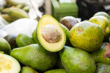 Sliced avocado with nuts inside and fresh green avocado market