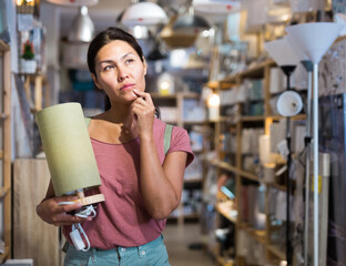 Portrait of asian woman customer choosing table lamp at store of household goods