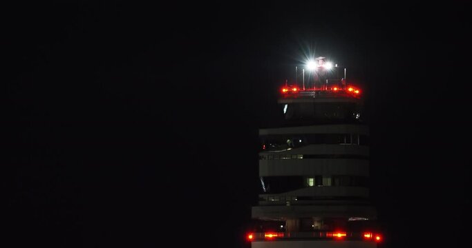 Illuminated control tower with airplane in distance