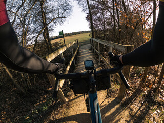 Riding a gravel bike crossing a tight wooden bridge rider point of view