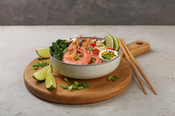 Delicious ramen with shrimps, egg in bowl and chopsticks on light textured table. Noodle soup