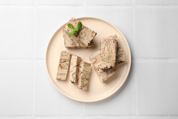 Tasty chocolate halva with mint on white tiled table, top view
