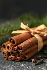 Different spices. Aromatic cinnamon sticks and clove seeds on dark gray textured table, closeup
