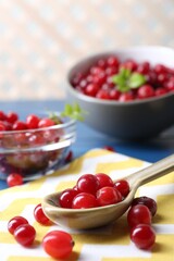 Spoon with fresh ripe cranberries on table, closeup